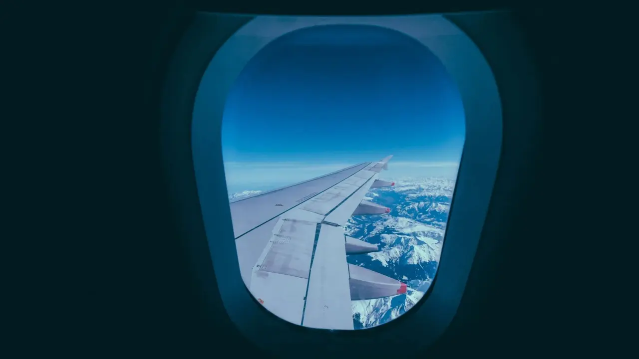 Aircraft wing seen through a window above clouds