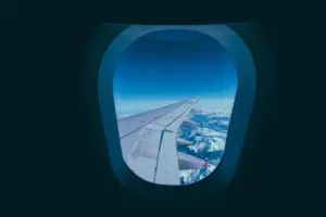 Aircraft wing seen through a window above clouds